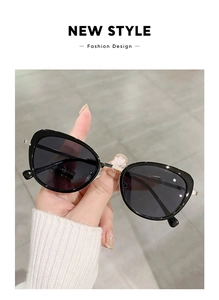 Close-up of retro cat-eye sunglasses with black frame and silver metal temples held in hand