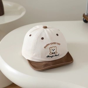 Détail du bonnet en coton pour bébé avec broderie ours et visière souple marron sur table