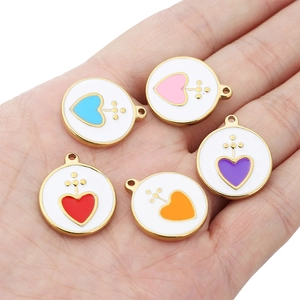 Golden round stainless steel enamel heart charms in five colors shown in palm