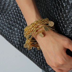 Detail of bohemian gold multi-layer bracelet featuring coin pendants on a female wrist