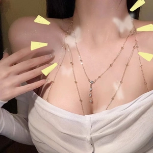Detail of layered gold body chain featuring delicate beads and a sparkling diamond pendant