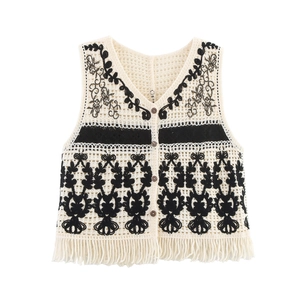 Detail of bohemian knit waistcoat featuring ethnic embroidery and long fringe hemline