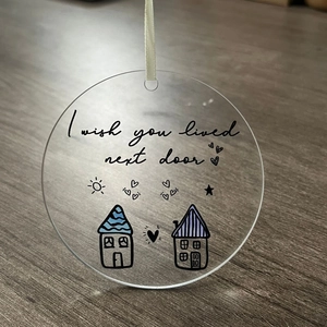 Detail view of transparent acrylic Christmas ornament with I wish you lived next door text