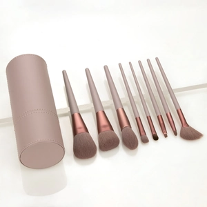 Detailed view of nine dusty pink makeup brushes with rose gold ferrules and a PU storage tube