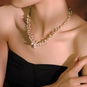 Elegant vintage necklace with white pearls and gold metal pendant worn by a model