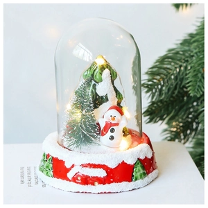 Detail of a Christmas glass dome with LED lights, snowman and mini tree on a red base