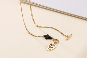 Detail of gold skull necklace featuring black cross and natural turquoise with T-bar clasp