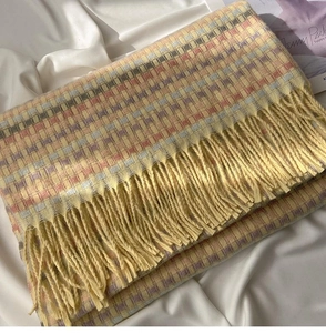 Close-up of yellow rainbow plaid scarf with soft cashmere texture and long fringe details
