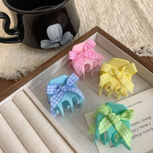 Colorful floral bow hair claws in macaron pastel shades on a wooden display tray