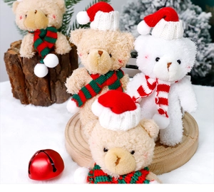 Close-up of plush Christmas bears with red hats and scarves on a snowy festive background