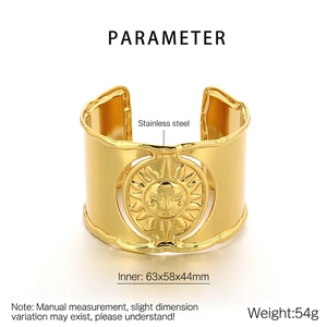 Detail of gold wide cuff bangle with embossed sun face pattern and steel texture