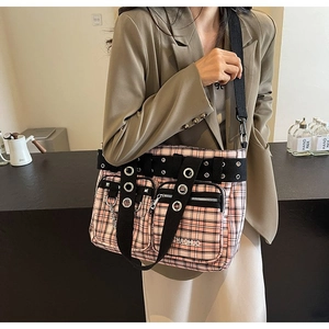 Detailed view of pink plaid tote bag with black straps and metallic ring decoration