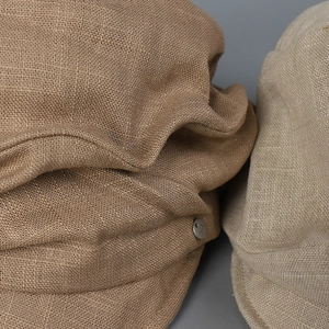 Detailed macro shot of linen texture and metal buttons on baker boy caps