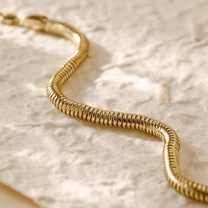 Macro shot of 14K gold plated snake chain bracelet with fine metallic texture