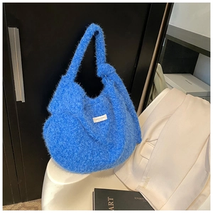 Detail showing plush blue faux fur texture and a woven label on a hobo shoulder bag