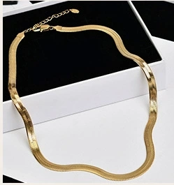 Close-up of a 14K gold-filled flat snake chain necklace on a minimalist jewelry box