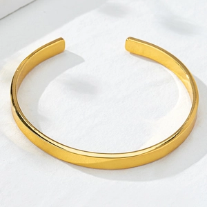 Detail of polished golden open bangle featuring a minimalist geometric design and smooth finish