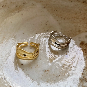 Macro view of layered wavy 925 silver rings in gold and silver on ceramic plate