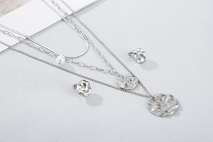 Close-up of silver multi-layer necklace with hammered round pendants and pearl detail