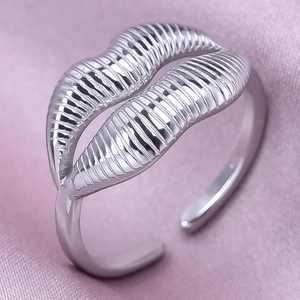 Macro detail of adjustable lip shaped silver ring on silky purple fabric backdrop