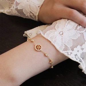 Detailed shot of a gold eight-pointed star compass bracelet worn by a female model