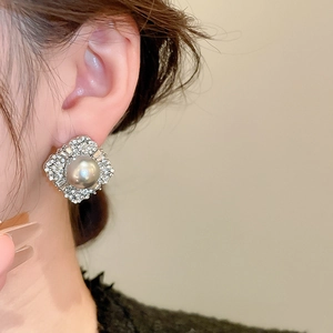 Close-up of elegant silver stud earrings with grey pearl and sparkling rhinestones on model