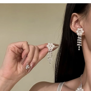 Detail of silver drop earrings featuring pearls, rhinestones, and elegant flower tassels