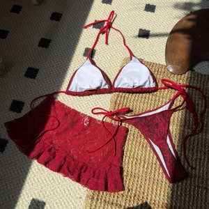 Vue détaillée de la texture du bikini en dentelle rouge et des motifs floraux ajourés