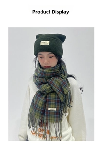 Detail of green plaid scarf with tassels and matching knit beanie on model