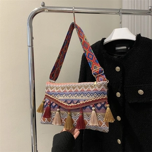 Detail of bohemian woven crossbody bag featuring colorful tassels and embroidered strap