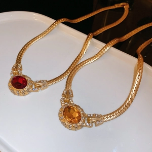 Detail view of vintage gold snake chains with red and amber oval crystal pendants