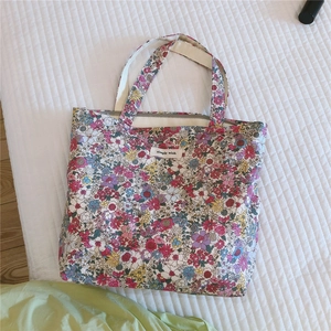 Détail du sac cabas en coton à fleurs avec fermeture éclair et étiquette de marque