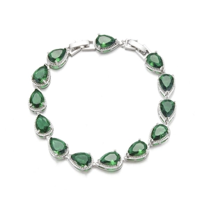Macro detail of tear-drop emerald bracelet with silver base and crystal halo