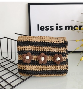 Detail of hand-woven striped clutch featuring three brown knitted flowers and zipper closure