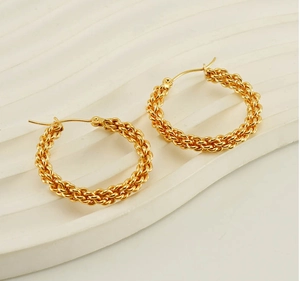 Dettaglio di orecchini a cerchio intrecciati placcati oro 18K su un piatto decorativo