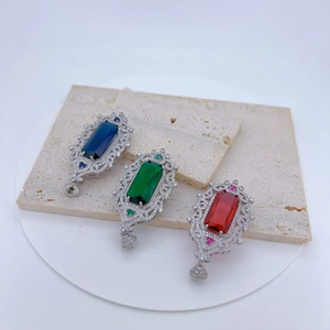 Detail of vintage silver pendants with blue, green, and red gems on a stone slab