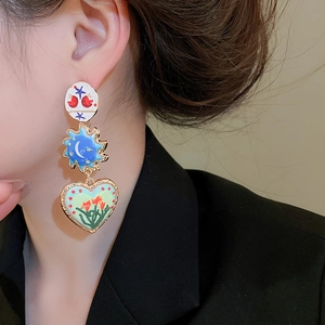 Detail of colorful enamel heart and sun earrings with gold accents on a model
