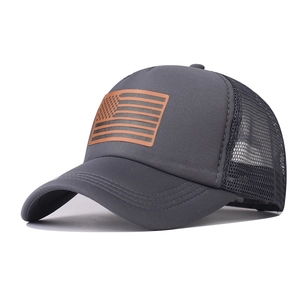 Detail view of American flag patch on a dark grey mesh trucker cap with reinforced visor
