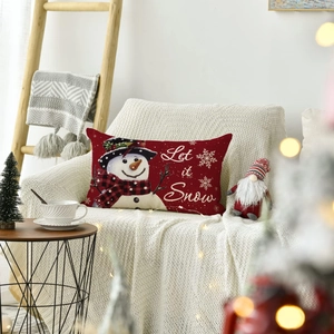 Cozy Christmas lumbar pillow with snowman pattern and Let it Snow text on a sofa