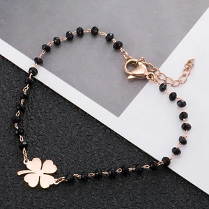 Detail of rose gold chain bracelet with black faceted beads and clover charm