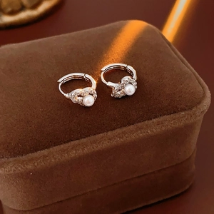 Close-up of silver zircon hollow gourd pearl hoop earrings on a brown velvet jewelry box
