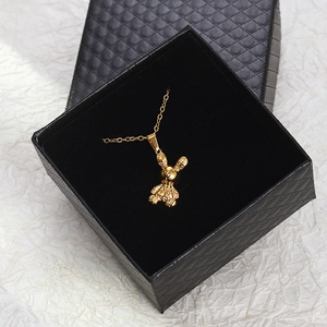 Polished 18K gold rabbit pendant necklace with monogram pattern in a black jewelry box