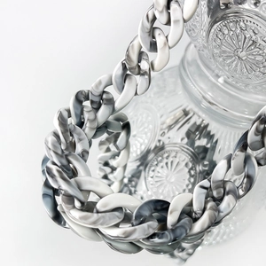 Detailed view of thick marble-textured acrylic chain links on textured glassware