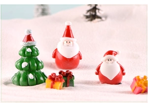 Miniature Christmas scene with Santa Claus figurines, snowy tree and colorful gift boxes