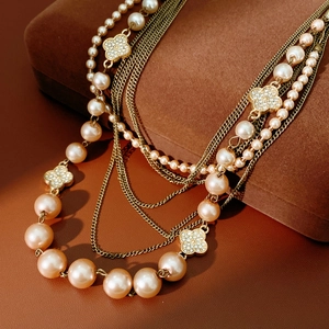 Detailed macro of layered necklace with champagne pearls and sparkling clover pendants