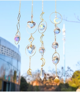 Detail of hanging crystal suncatchers with moon and star charms against a clear blue sky