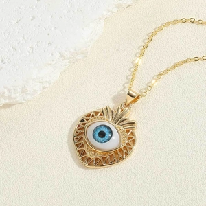 Close-up of golden heart evil eye pendant with blue iris detail and sunburst texture