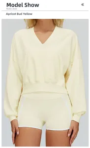 Close-up of the front pocket and drop shoulder seams on an apricot yellow hoodie