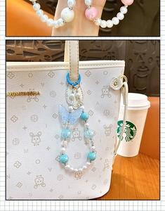 Detail of a glowing blue butterfly beaded charm on a white handbag with rabbit patterns.