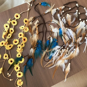 Detailansicht von Boho-Haarschmuck mit Sonnenblumen-Stirnband und bunten Federquasten